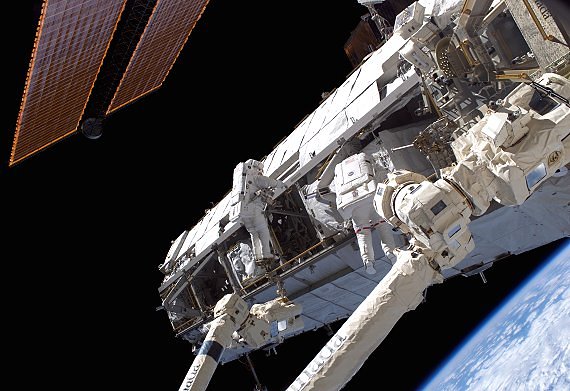 Tv astronauter under en rymdpromenad vid rymdstationens horisontella fackverkskonstruktion