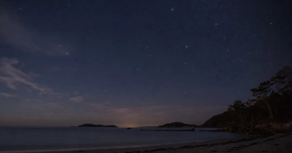 Sydlig natt över en stilla strand med gles men klar stjärnhimmel