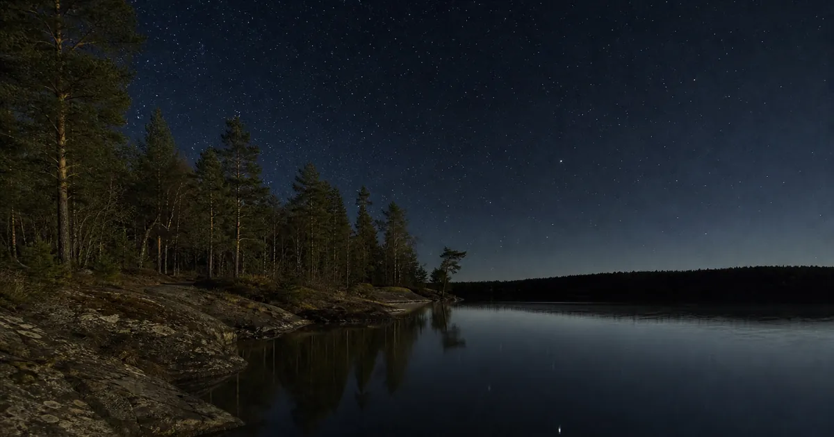 Klar aprilnatt över en skogssjö med mycket mörk himmel