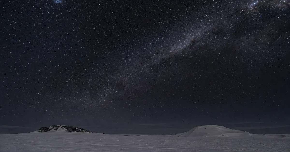 Mycket mörk sydhimmel nära himmelspolen över ett avlägset snöfält