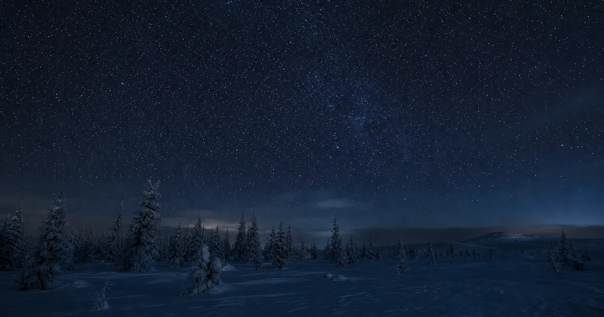 Mycket mörk vinternatt över ett vidsträckt snöfält i norra Sverige