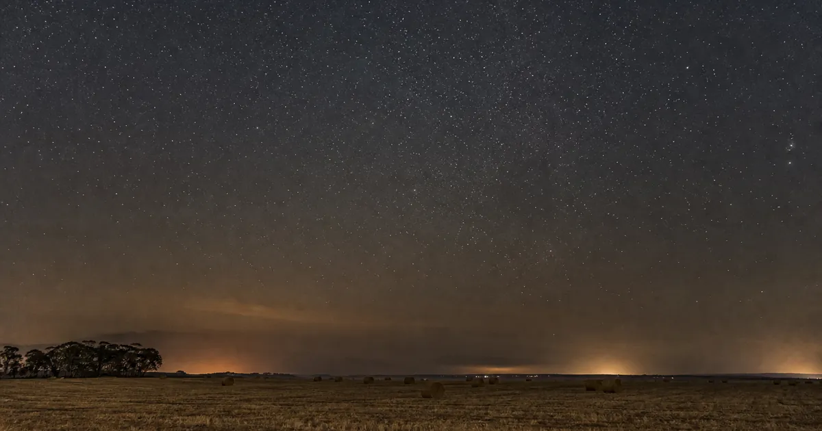 Sydlig natt över torr jordbruksmark med svag stjärnhimmel