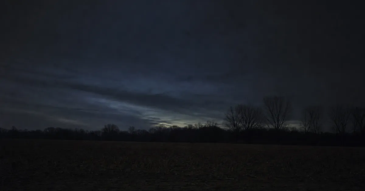 Mörk senvinternatt över ett kalt fält med nästan tom himmel i söder